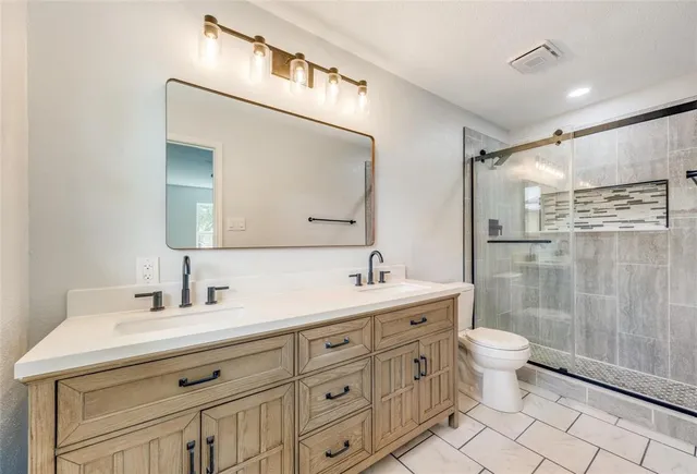 a bathroom with a double vanity sink a toilet and a mirror