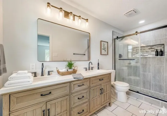 a bathroom with a double vanity sink mirror and toilet