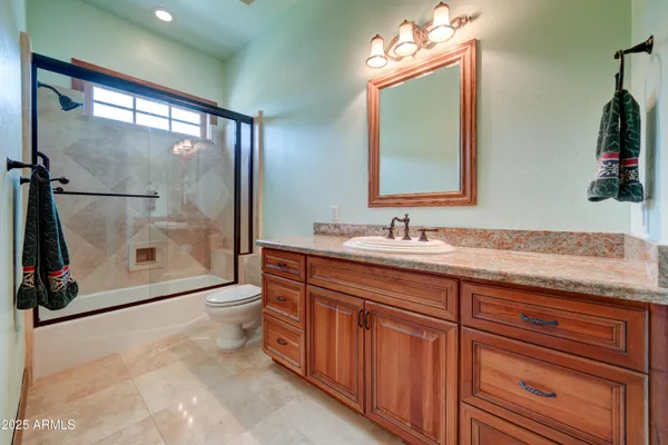 a bathroom with a granite countertop sink a toilet and mirror