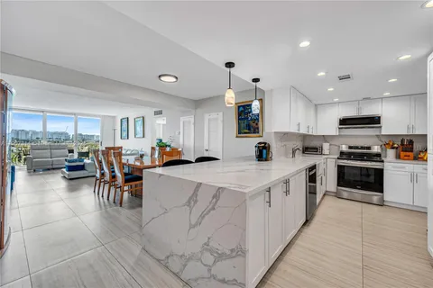 a large white kitchen with lots of counter space and stainless steel appliances