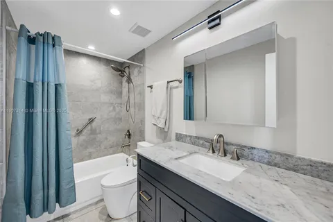 a bathroom with a granite countertop sink toilet mirror and shower