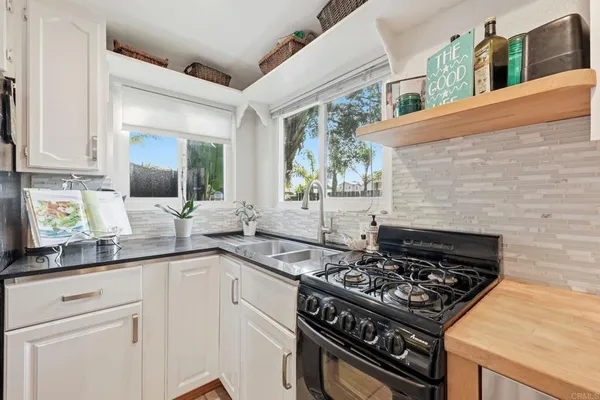 a kitchen with stainless steel appliances granite countertop a refrigerator a sink and white cabinets