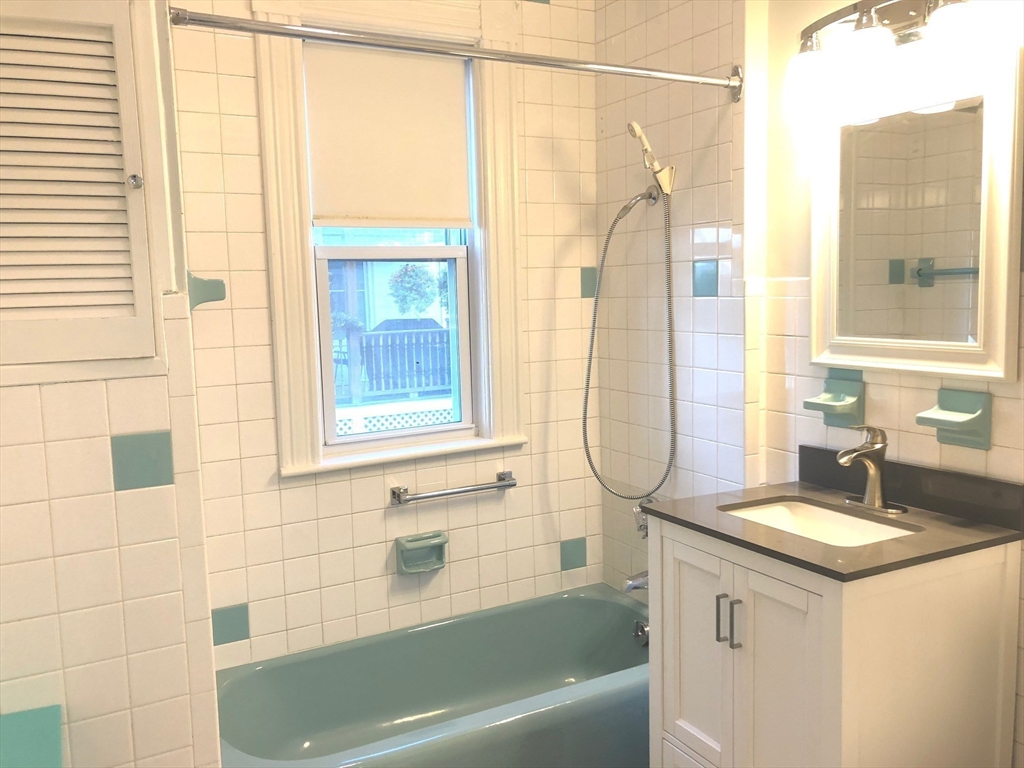 505 High Street, Unit 505 Lowell, MA 01852 - Photo 12 of 17 a bathroom with a granite countertop sink and a bathtub