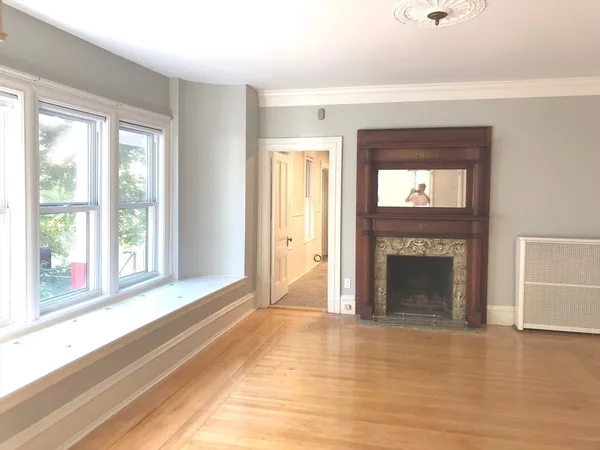 a view of an empty room with window and fire place