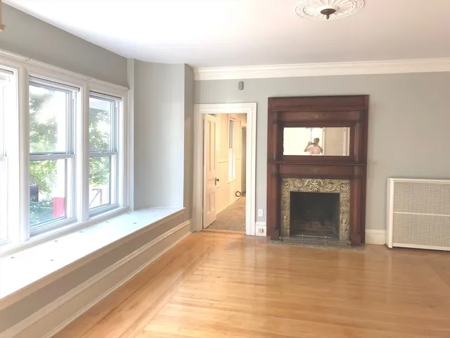 a view of an empty room with window and fire place