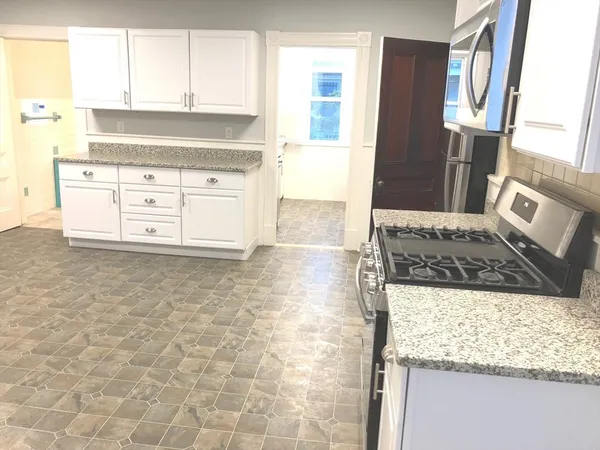 a kitchen with granite countertop a sink stove and cabinets