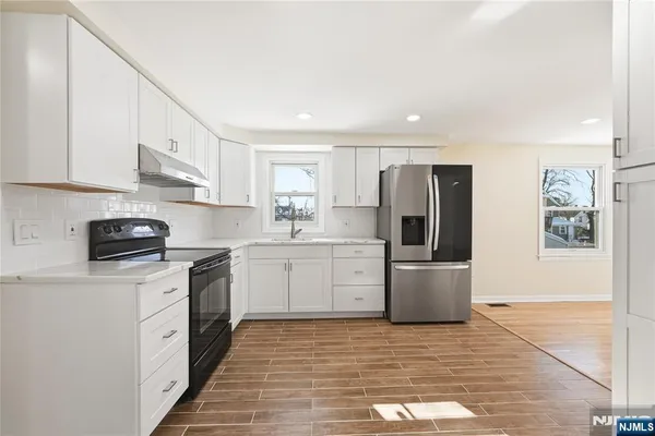 a kitchen with a sink stainless steel appliances and white cabinets