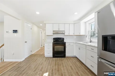 a large white kitchen with wooden floor and white cabinets