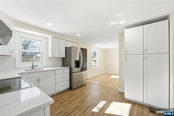 a large white kitchen with wooden floor and white cabinets