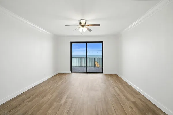 an empty room with wooden floor chandelier fan and windows