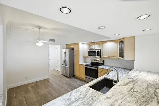 a kitchen with granite countertop a refrigerator stove and sink
