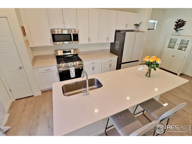 a kitchen with stainless steel appliances a sink a stove a microwave a refrigerator a counter space and cabinets