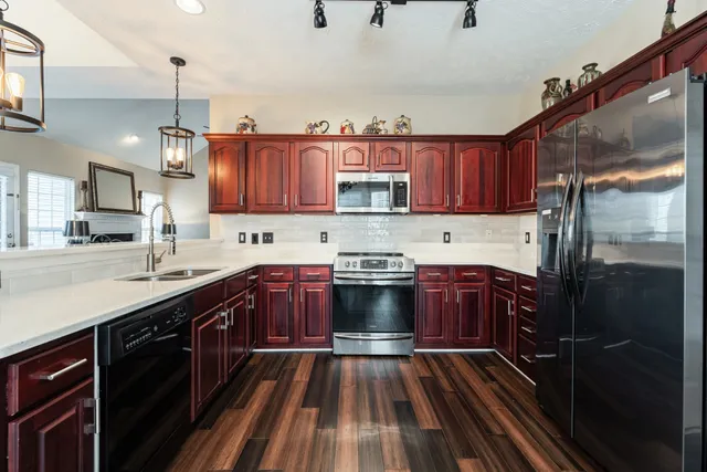 a kitchen with stainless steel appliances granite countertop a refrigerator a sink dishwasher a stove and white countertops with cabinets