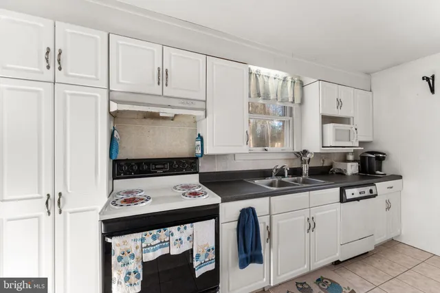 a kitchen with granite countertop a sink stove and cabinets