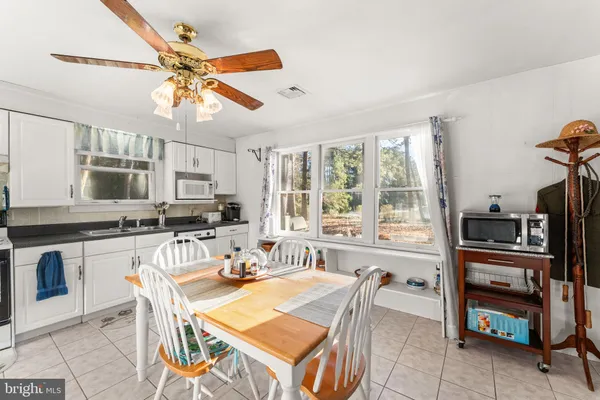 a kitchen with stainless steel appliances kitchen island granite countertop a refrigerator a stove a sink a dining table and chairs with wooden floor