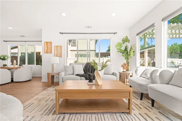 a living room with furniture large windows and wooden floor