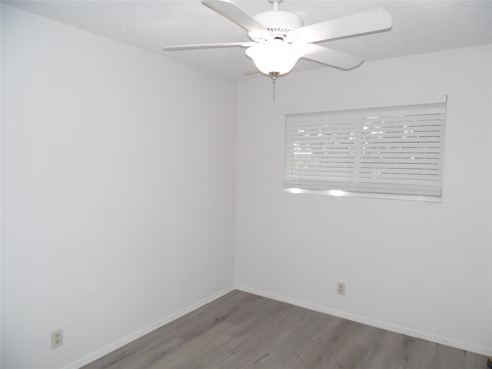 7400 Dixie Drive, Unit B Austin, TX 78744 - Photo 13 of 15 Room featuring gray wood-finish flooring, white walls, and a window with horizontal blinds