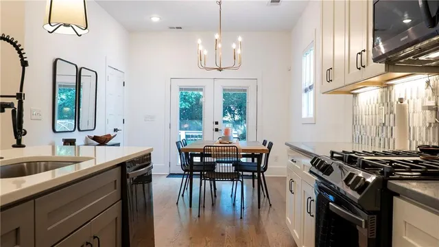 a kitchen with stainless steel appliances granite countertop a stove a sink dishwasher a dining table and chairs with wooden floor