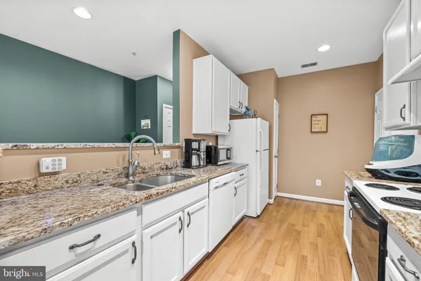 a kitchen with granite countertop a sink stove and refrigerator