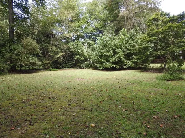 a view of a yard with large trees and wooden fence