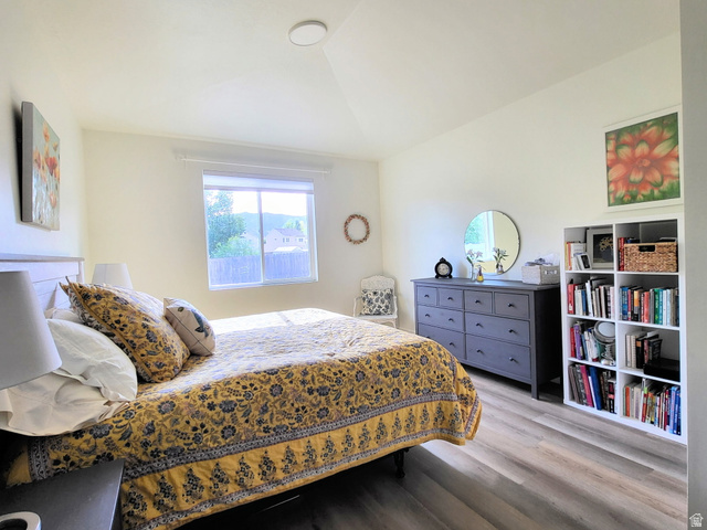 683 Kings Landing Tooele, UT 84074 - Photo 16 of 39 Bedroom featuring wood-finish flooring, a contemporary ceiling light fixture, a window with exterior views, and neutral wall tones
