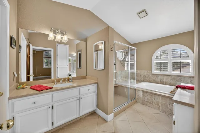 a spacious bathroom with a granite countertop tub a double vanity sink a mirror and next to a window