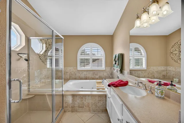 a bathroom with a tub sink mirror and a shower