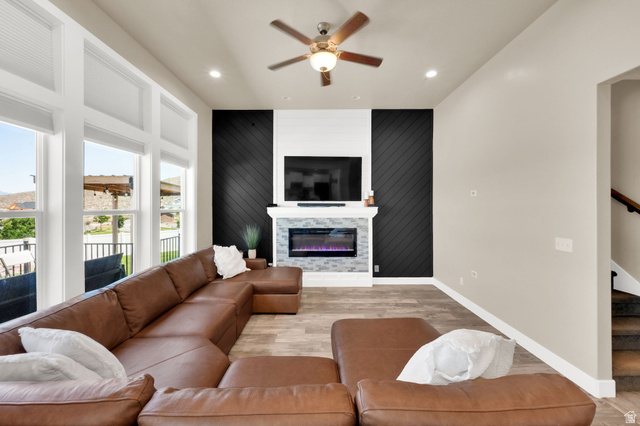 1857 Thunder Gulch Road Eagle Mountain, UT 84005 - Photo 16 of 50 Living area featuring an electric fireplace with a stone tile surround and white mantel, flanked by accent walls with diagonal wood paneling