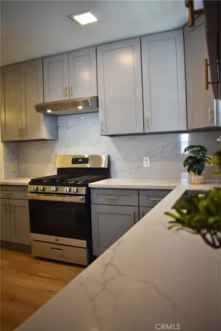 a kitchen with stainless steel appliances granite countertop a stove a sink and a white cabinets