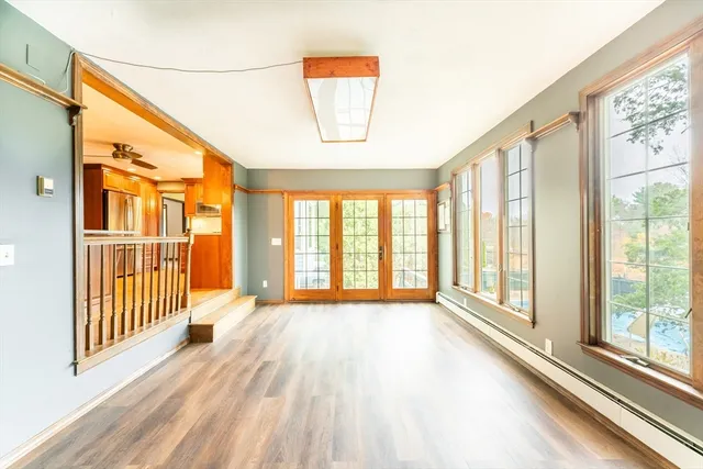 a view of an empty room with wooden floor and a window
