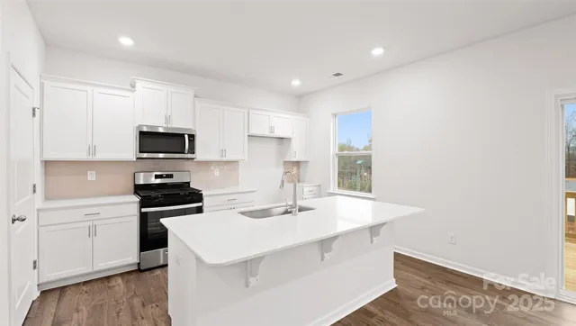 a kitchen with a sink a stove a microwave and cabinets