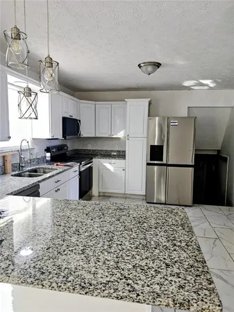 a kitchen with granite countertop a refrigerator and a stove top oven