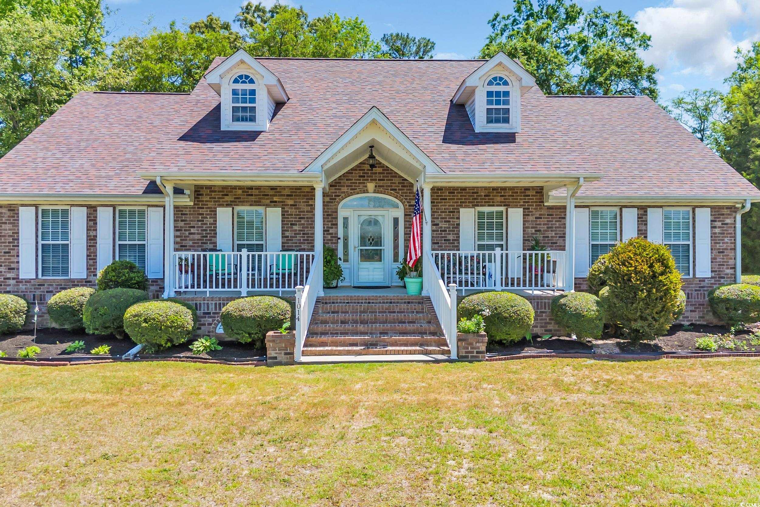 New england style home with a porch, brick siding,