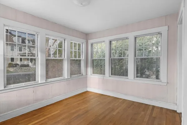 a view of an empty room with a window and wooden floor