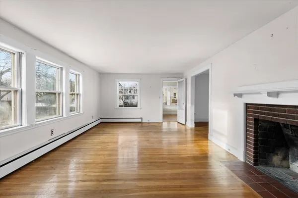 a view of an empty room with window and wooden floor