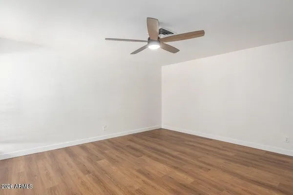 a view of a room with wooden floor ceiling fan and window