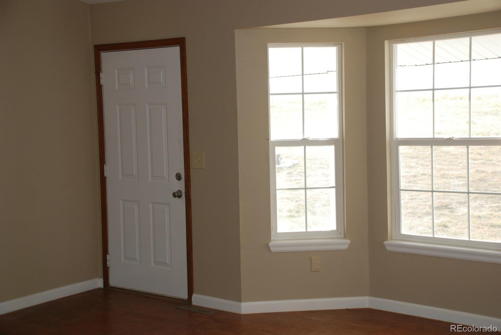 8979 Lariat Loop Elizabeth, CO 80107 - Photo 13 of 17 an empty room with wooden floor and windows