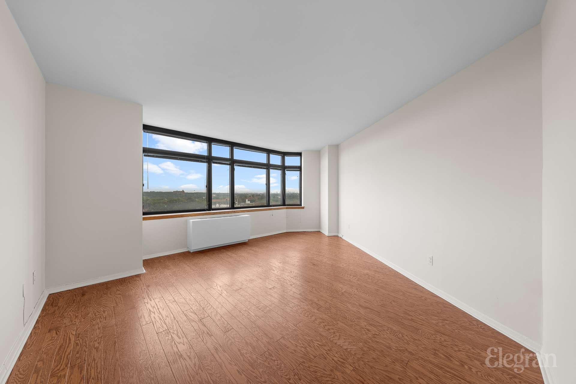 112-01 Queens Boulevard, Unit 16F Queens, NY 11375 - Photo 5 of 24 an empty room with wooden floor and windows