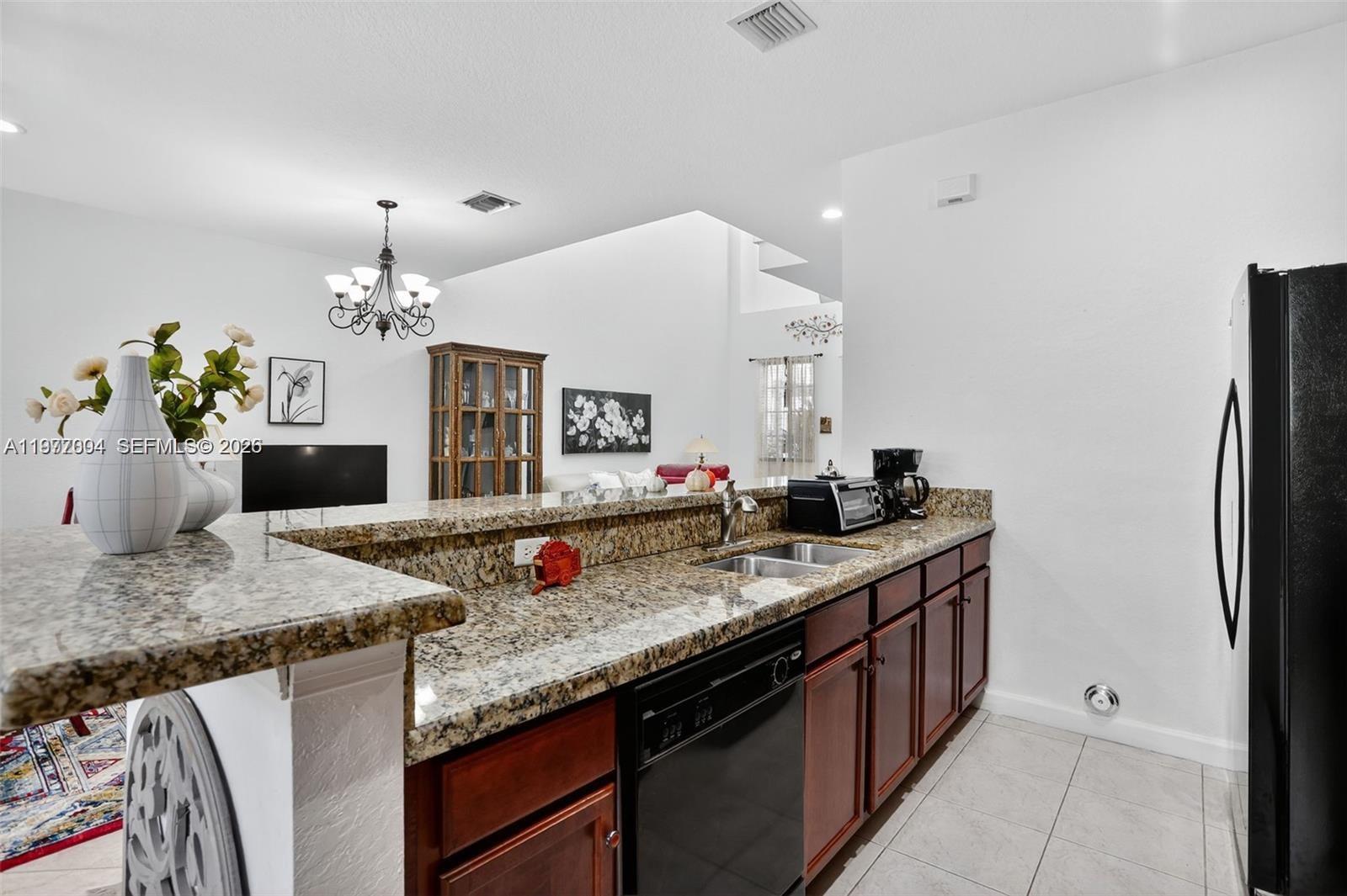 728 Southeast 2nd Street Pompano Beach, FL 33060 - Photo 6 of 22 a kitchen with granite countertop a sink and white cabinets