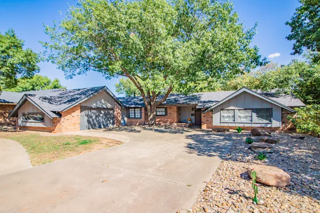 a view of a house with a yard and large tree