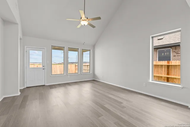 a view of an empty room with a window and wooden floor