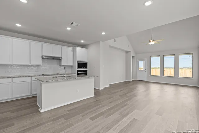 a kitchen with stainless steel appliances granite countertop a stove top oven a sink and a granite counter tops with wooden floors