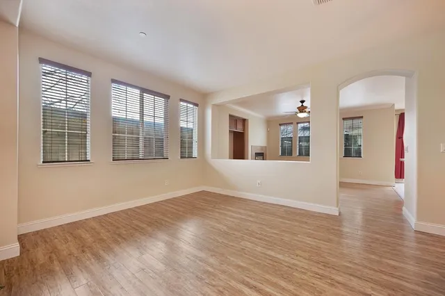 a view of an empty room with wooden floor fireplace and a window