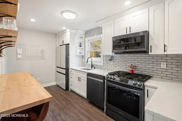 a kitchen with stainless steel appliances a stove a sink cabinets and a wooden floor