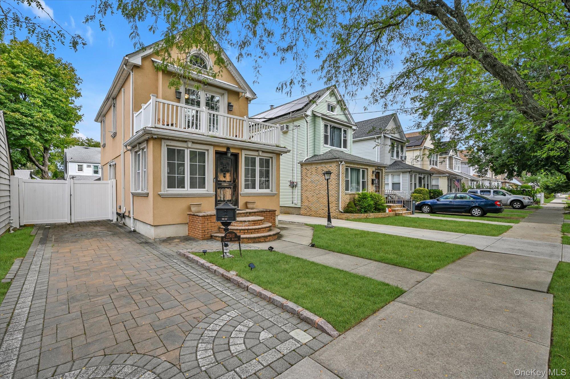 View of front of home featuring stucco siding, a balcony, and a gate