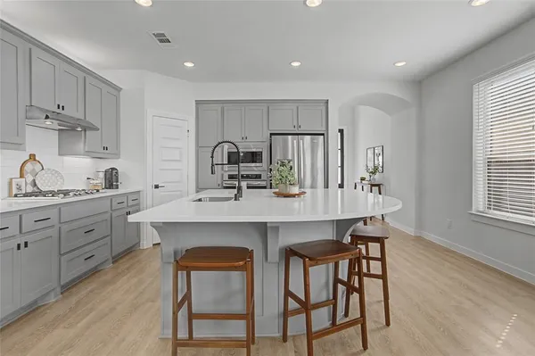 a kitchen with stainless steel appliances a sink a stove a refrigerator cabinets and dining table