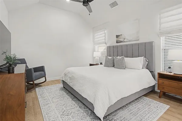 a bedroom with a bed and a potted plant on the dresser