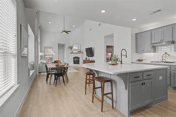 a kitchen with cabinets a sink dishwasher a dining table and chairs with wooden floor