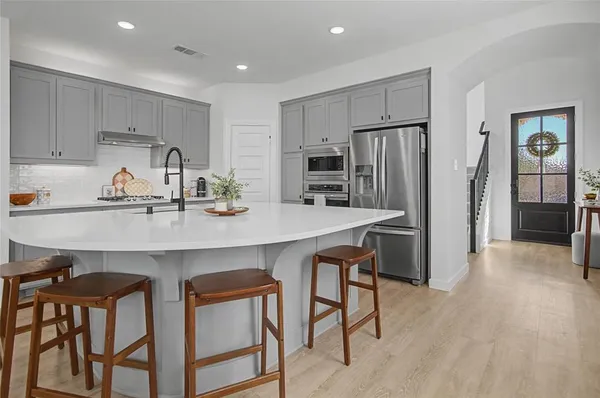 a kitchen with stainless steel appliances a dining table chairs refrigerator and sink