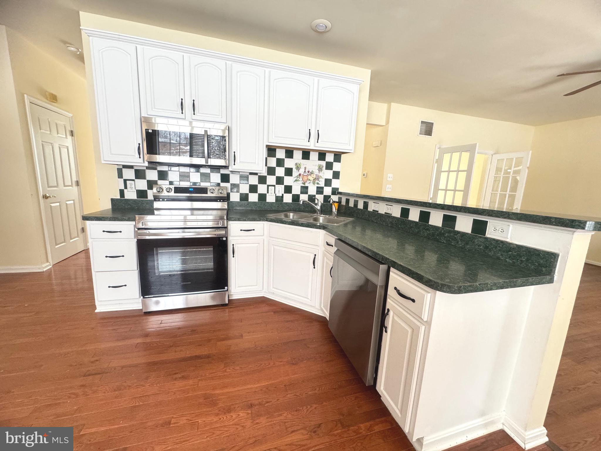 14410 Stottlemyer Road Smithsburg, MD 21783 - Photo 9 of 24 a kitchen with stainless steel appliances granite countertop a sink stove and white cabinets